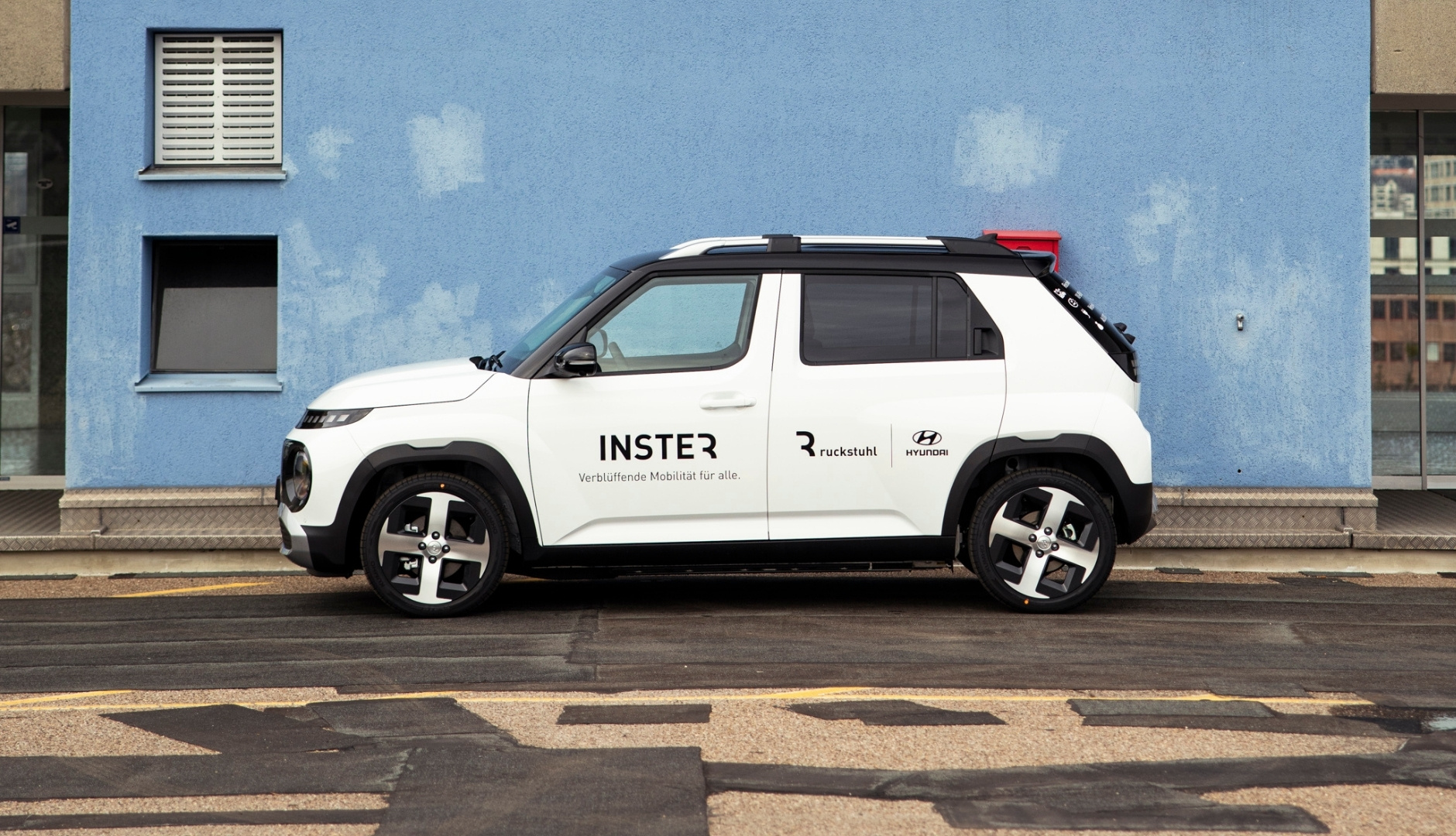 Weisser Hyundai SUV vor blauer Wand mit Ruckstuhl Garagen Branding.