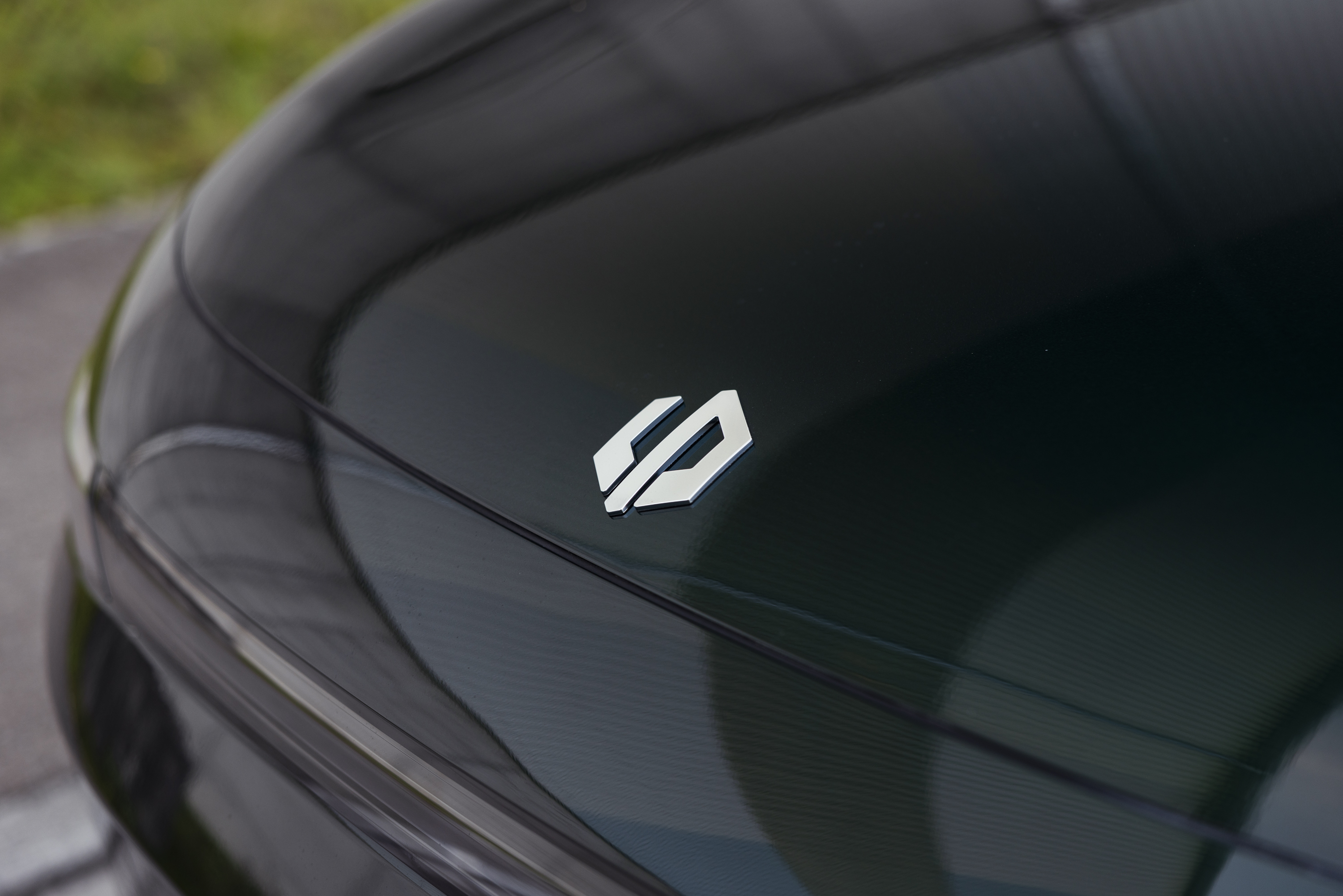 Nahaufnahme eines Fahrzeugemblems auf einer glänzenden Motorhaube.