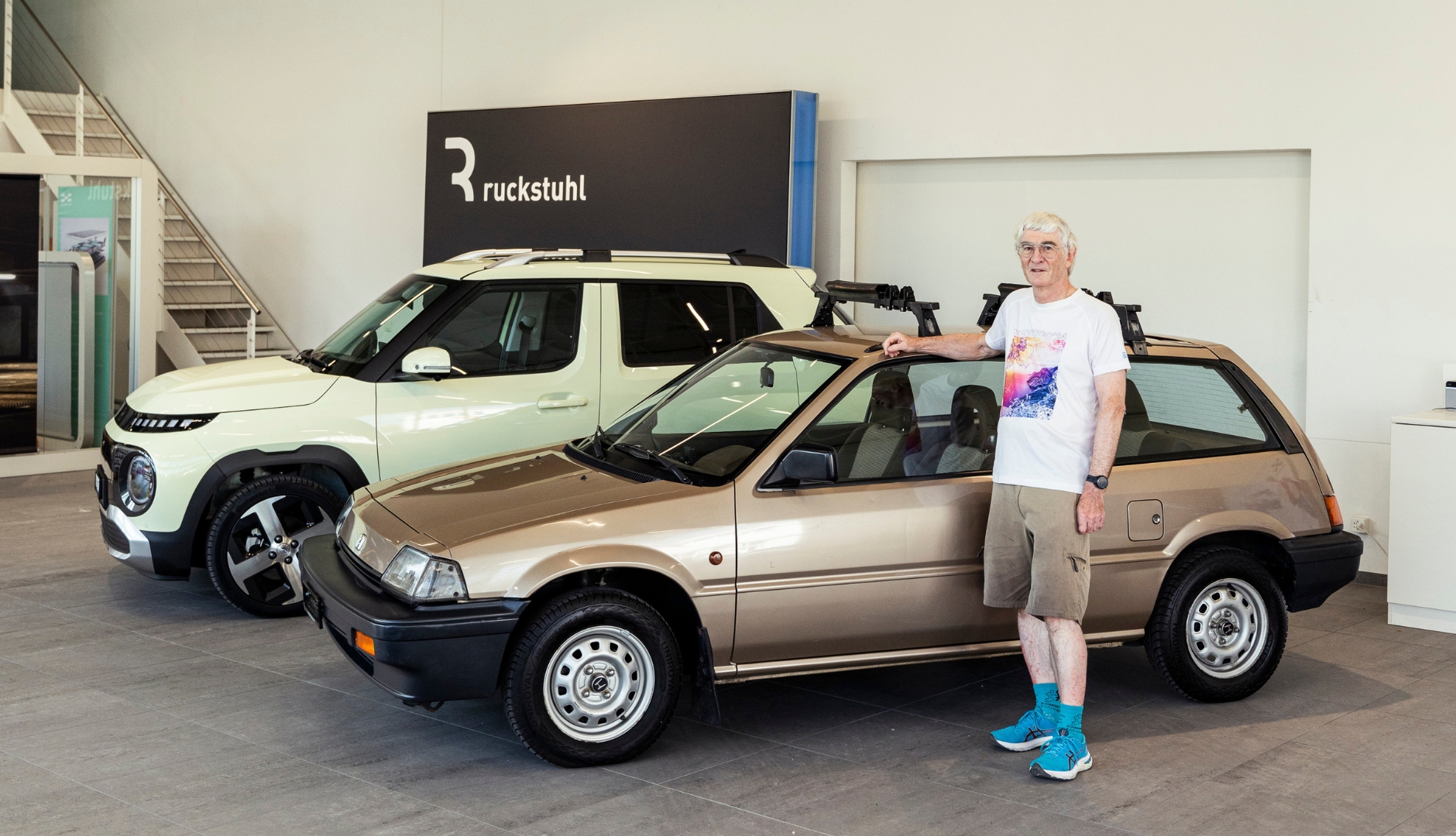 Eine Person steht neben zwei Autos im Ausstellungsraum der Ruckstuhl Garagen.
